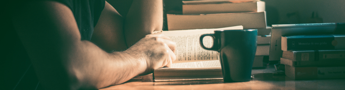 Someone studying with a pile of books and a coffee