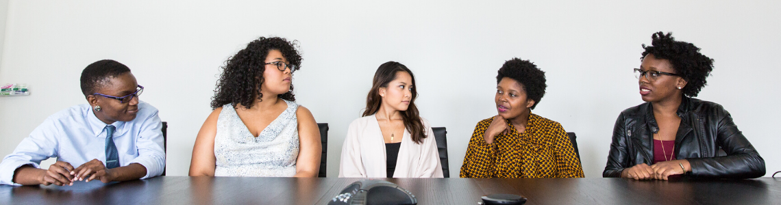 Five people sat behind a desk looking at each other